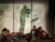 Violinist plays behind shadow wall, young performers pose asleep in front of it