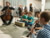 Children and a cellist make music in the foreground, orchestra musicians are in the background