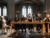 Singers sitting singing at a long table